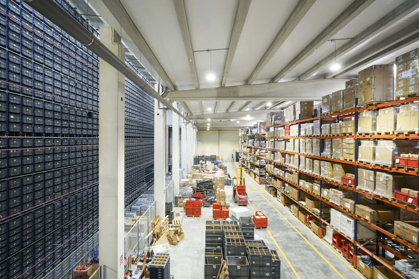 A bright warehouse aisle with picking carts and stocked shelving
